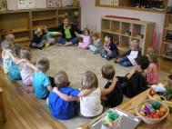 kids sitting in square-shaped 'circle,' their arms on each others' shoulders