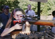 girl looking through rifle scope at firing range