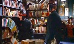 Montag's captain with his arm sweeping books off of a shelf